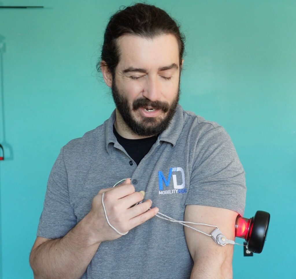 Dr. John using the achedaway cupper on his left tricep to hep reduce pain in his elbow while it is extended